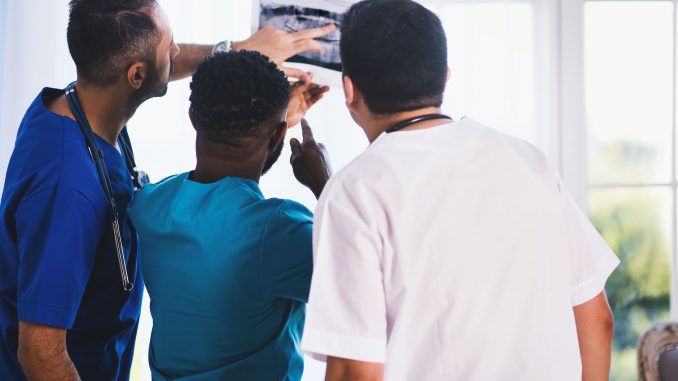 three person looking at x ray result