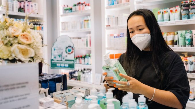 woman in black shirt holding a hand sanitizer bottle