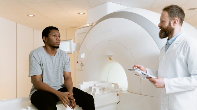 photo of man sitting on a ct scanner