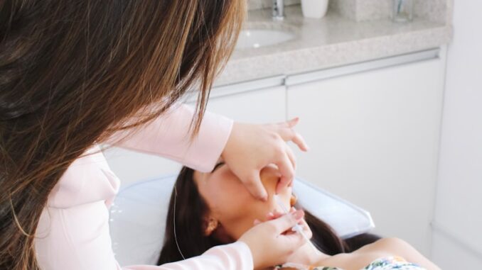 A woman getting her teeth brushed by another woman