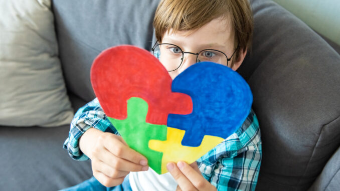 Preteen boy holding puzzle jigsaw heart shape, child mental health concept, world autism awareness day, teen autism spectrum disorder awareness concept