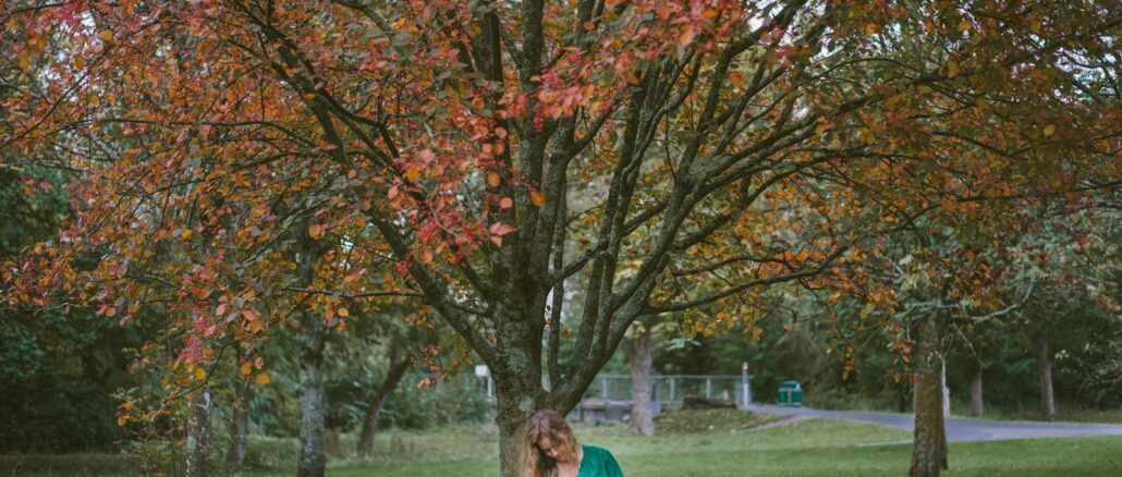 woman holding baby sitting under the tree