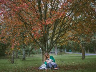 woman holding baby sitting under the tree