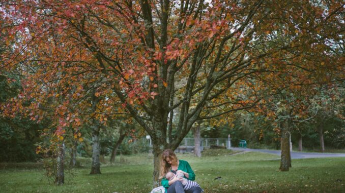 Photo by Dave Clubb woman holding baby sitting under the tree