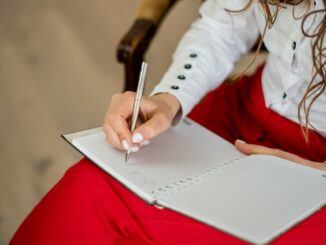 woman in white long sleeve shirt writing on white paper