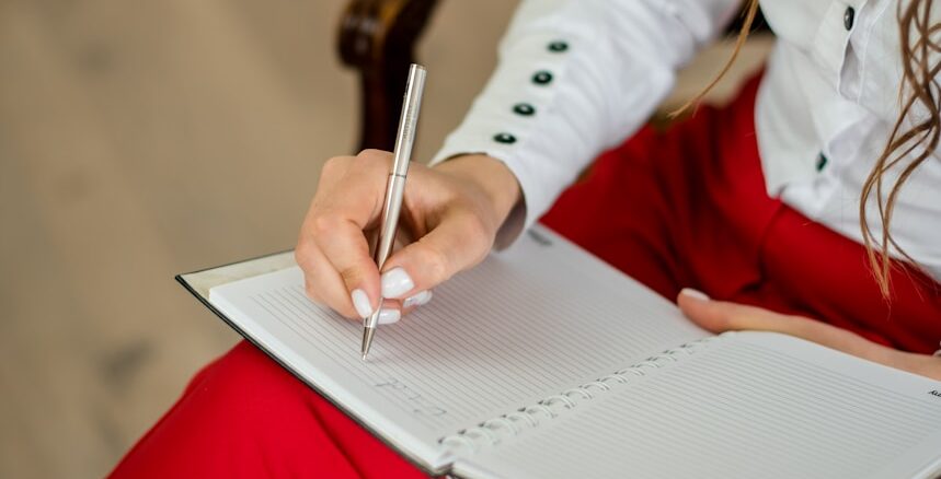 woman in white long sleeve shirt writing on white paper