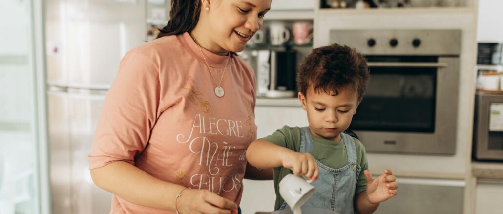 A joyful mother and son team up in the kitchen, enjoying a fun cooking session together.