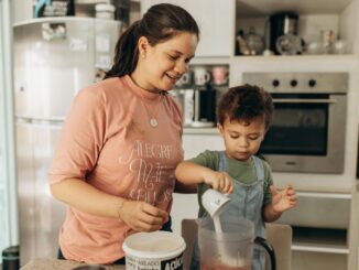 A joyful mother and son team up in the kitchen, enjoying a fun cooking session together.