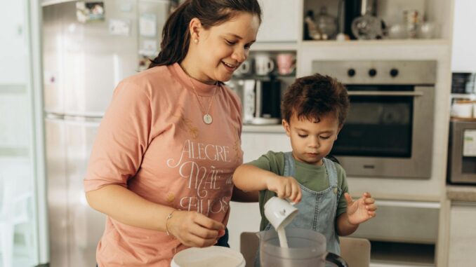 A joyful mother and son team up in the kitchen, enjoying a fun cooking session together.