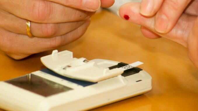 person putting blood on glucometer