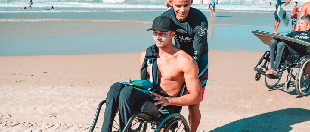 man in black shorts sitting on black wheelchair on beach during daytime