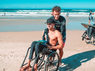 man in black shorts sitting on black wheelchair on beach during daytime