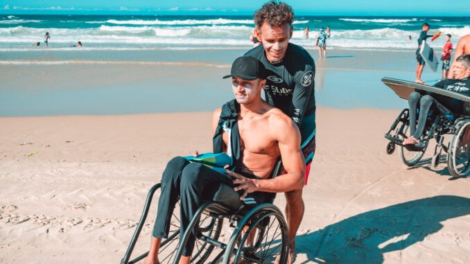 man in black shorts sitting on black wheelchair on beach during daytime